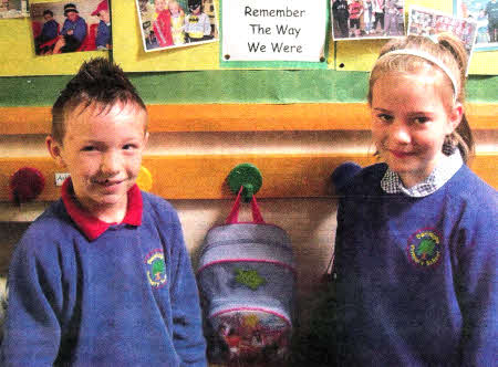 Derriaghy Primary pupils Jason Guiney and Hannah Mcquaide, two of this year's winners in the Lisburn Arts competition, look at the school board celebrating the school in photographs - some of which will be on display on the evening of the service in Derriaghy Parish Church.