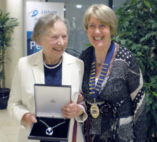 Mrs Gertie Reid, President of Magheragall WI, congratulates Joan Ormonde, winner of the star prize, a silver necklace donated by Midas Jewellers at the charity concert to celebrate the 60th anniversary of Magheragall WI.