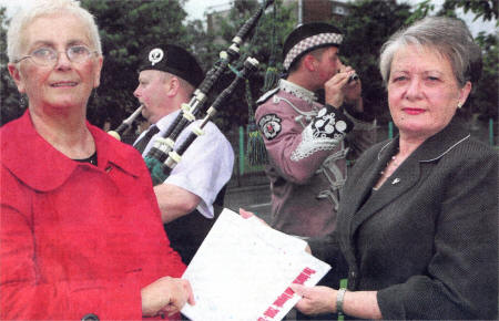 Jean Brown, Suffolk Lenadoon Interface Group Chairperson and Renee Crawford, Lenadoon Community Forum with members of Upper Falls Protestant Boys Flute Band and Gleann Chollain Irish Pipe Band who played together at the strategy launch.