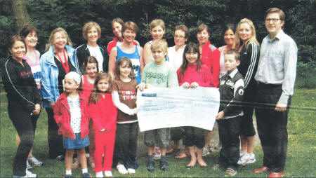 Some of the Hillsborough ladies who raised money for Ulster Cancer Foundation and War on Want, with their children, presenting a cheque to Eamon Quinn from War on Want.