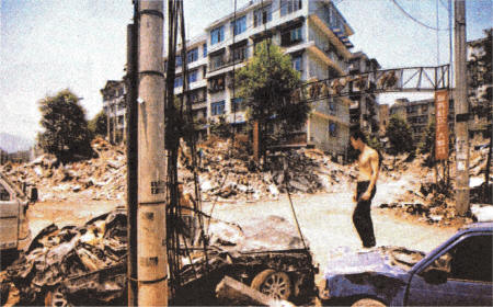 An earthquake survivor stands on a car among the rubble of a collapsed building following powerful earthquake in Dujiangyan, southwest China's Sichuan Province.