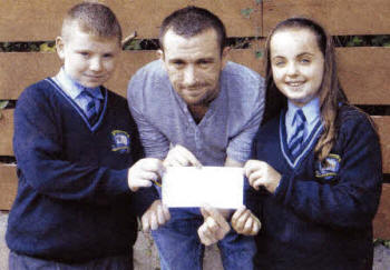 Ulster Star Photographer Aidan O'Reilly receives a cheque of £200 from St Joseph's primary School presenting the Cheque are pupils Conor Dickson and Rachel Roberts.