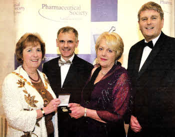 President Ms. Ann Bowen presenting Dr. Kate McClelland with her Fellowship medal, looking on are Mr. Raymond Anderson and Mr. Jim Wells MLA, Chair of the Northern Ireland Assembly's Health Committee.