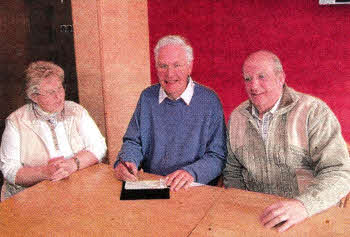 Branch Treasurer Stephen Anderson signing cheque for £4300. Looking on are Agnes McKissock, Vice-Chair and Raymond Flanagan, Assistant Treasurer.