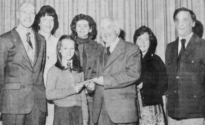 Jacqueline Campbell presents Mr. Graham with a wallet of notes. Others in the picture are Mr. Thomas Welch, principal; Mr. Derek Alien, vice-principal; Mrs. Margaret Clarke, senior mistress; Mrs. Pat Cochrane, head of the infant department, and Mrs. Nora McNally, secretary. E2301
