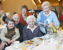 Joyce Moran (Chairperson of Lisburn Cancer Research Committee) pictured serving up a ‘Big Breakfast’ last Friday morning (3rd April) to Carol Campbell and her parents Thomas and Jeanette Weekes and grandson.