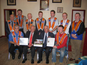Ronald and Ivor McCandless pictured at Quilly Orange Hall on Thursday 6th October 2005, presenting a framed history of Quilly Flute Band and captioned photographs of the Band and Lodge to Wilson Beggs - Worshipful Master (left) and Gareth Lough - Deputy Master (right) in memory of their father, the late Mr. George McCandless.  Included in the photo are L to R: (back row) Eric Jess - Deputy District Master and Lodge Chaplain, Walter Erwin - Secretary, Jim McCoosh, Philip Beggs, Aaron McMullan, Alan Roulston � Treasurer and Will Lough - Worshipful District Master, Lower Iveagh District No. 1.